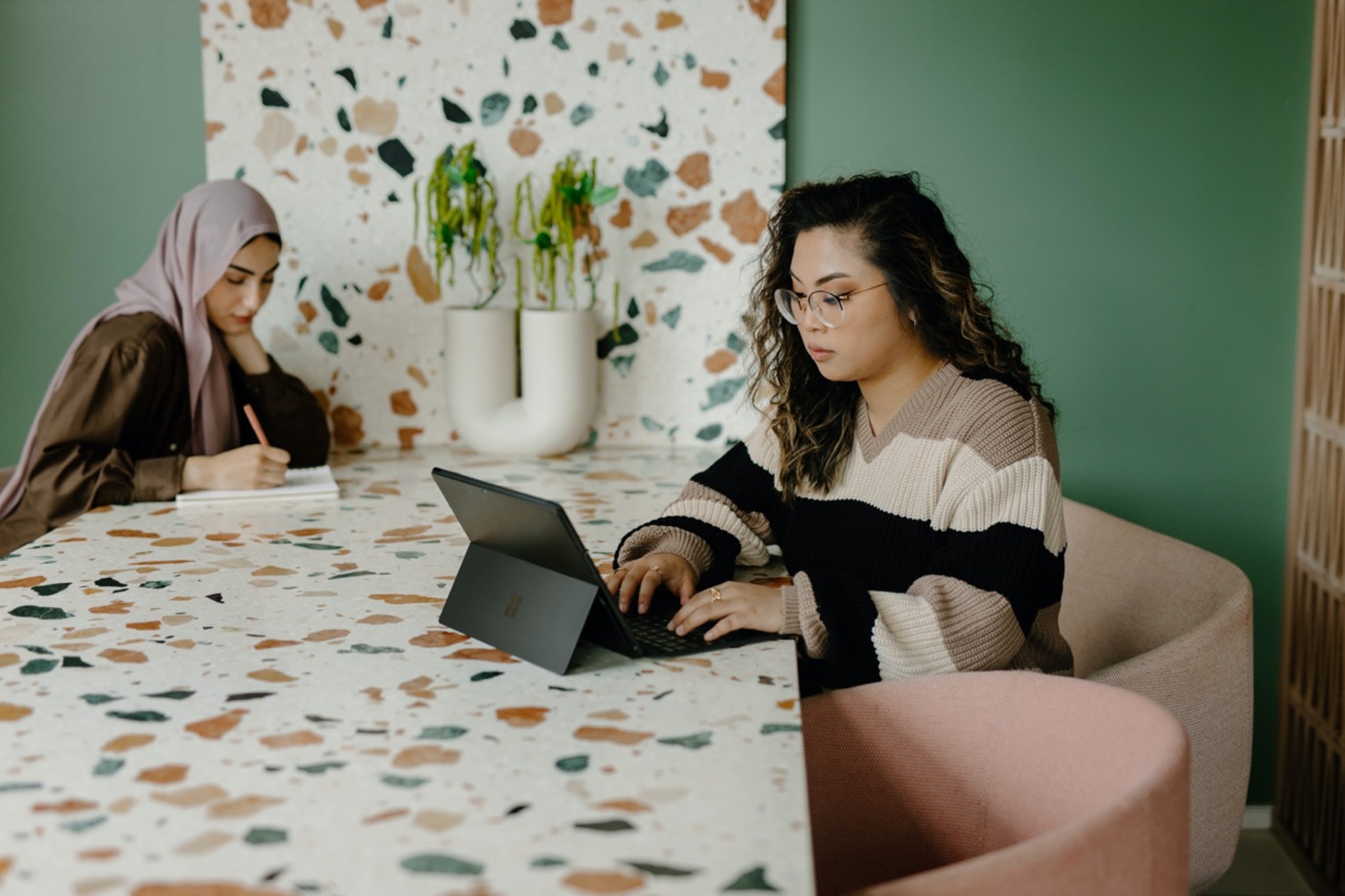 Two ladies sitting at a colourful table coworking in a meeting room 