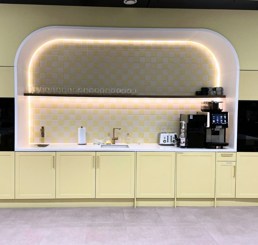 Butternut Box modern office kitchen area with curved backsplash, integrated lighting, and coffee station