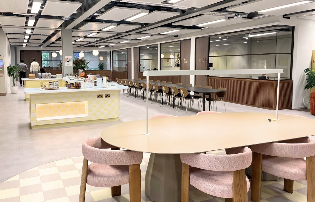 Butternut Box modern kitchen and dining area with white island, pink chairs, and communal seating
