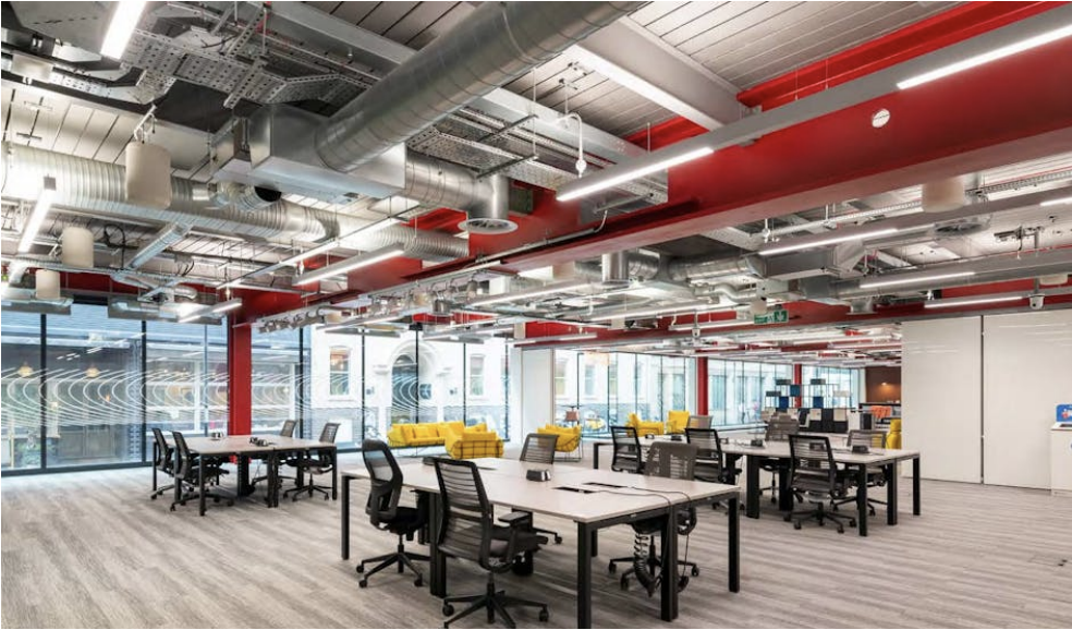Modern fintech office workspace with exposed red beams and yellow seating